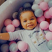 Kaïss participe au concours pour gagner de l'argent avec cette photo : child, toddler, smiling, ball_pit, pastel_colors, curly_hair, onesie, indoor, happy, playful, pink_balls, gray_balls, white_balls, cute, portrait, baby, leisure, cozy, relaxed, fun