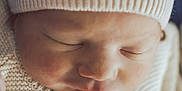 Hudson is registered to the contest to win money with this photo: baby, newborn, sleeping, close_up, face, beanie, knit_hat, sweater, cozy, infant, cheek, nose, lips, eyelashes, soft_light, portrait, skin_texture, peaceful, indoor, textured_fabric