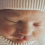 baby, newborn, sleeping, close_up, face, beanie, knit_hat, sweater, cozy, infant, cheek, nose, lips, eyelashes, soft_light, portrait, skin_texture, peaceful, indoor, textured_fabric