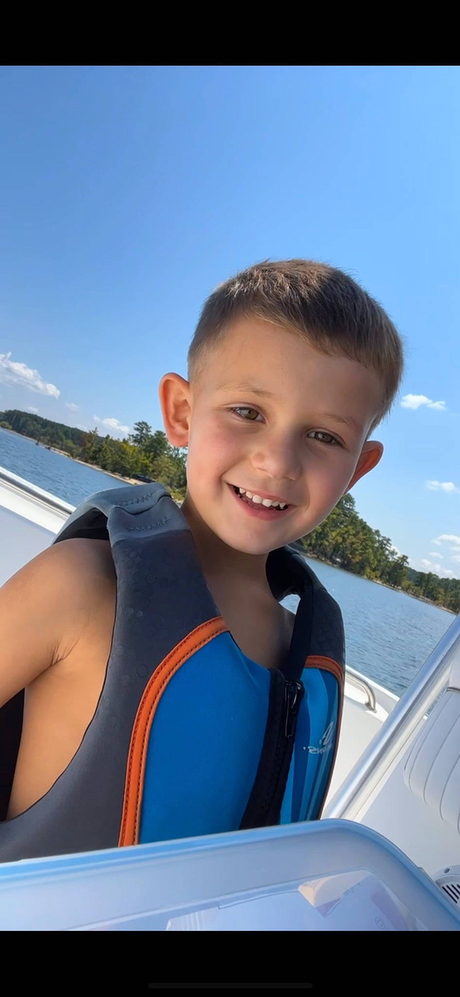 Jackson is registered to the contest to win money with this photo: boat, boats_and_boating_equipment_and_supplies, cloud, dry_suit, electric_blue, fun, happy, joy, lake, leisure, lifejacket, ocean, person, personal_protective_equipment, recreation, sky, smile, swimwear, travel, tree