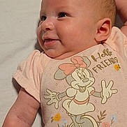 Emily is registered to the contest to win money with this photo: baby, infant, newborn, smiling, face, onesie, minnie_mouse, cartoon, lying_down, bed_sheet, arm, hand, video_call, screenshot, smartphone_ui, status_bar, portrait, happy, candid, clothing