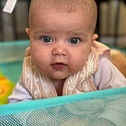 Hilona a rejoint le concours — aidez-le/la à gagner de superbes lots ! baby, baby_toy, bib, child, chubby_cheeks, closeup, clothing, curious, cute, eyes, face, head, indoor, infant, mesh, person, playpen, portrait, soft_lighting, toy