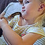 Gracelynn Marie is registered to the contest to win money with this photo: child, toddler, man, gecko, reptile, shoulder, striped_shirt, yellow, white, blue_jeans, couch, indoor, person, animal, pet, curious, blonde_hair, casual_clothing, seated, family