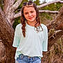 child, girl, smile, curly_hair, braids, casual_clothing, jeans, tshirt, outdoor, nature, tree, portrait, young, fashion, standing, happy, grass, sunlight, background, dimple