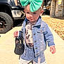 accessory, boots, casual, child, clothing, cute, daytime, denim_jacket, denim_shorts, fashion, handbag, large_bow, outdoor, person, playful, portrait, sidewalk, small_child, sunny, toddler