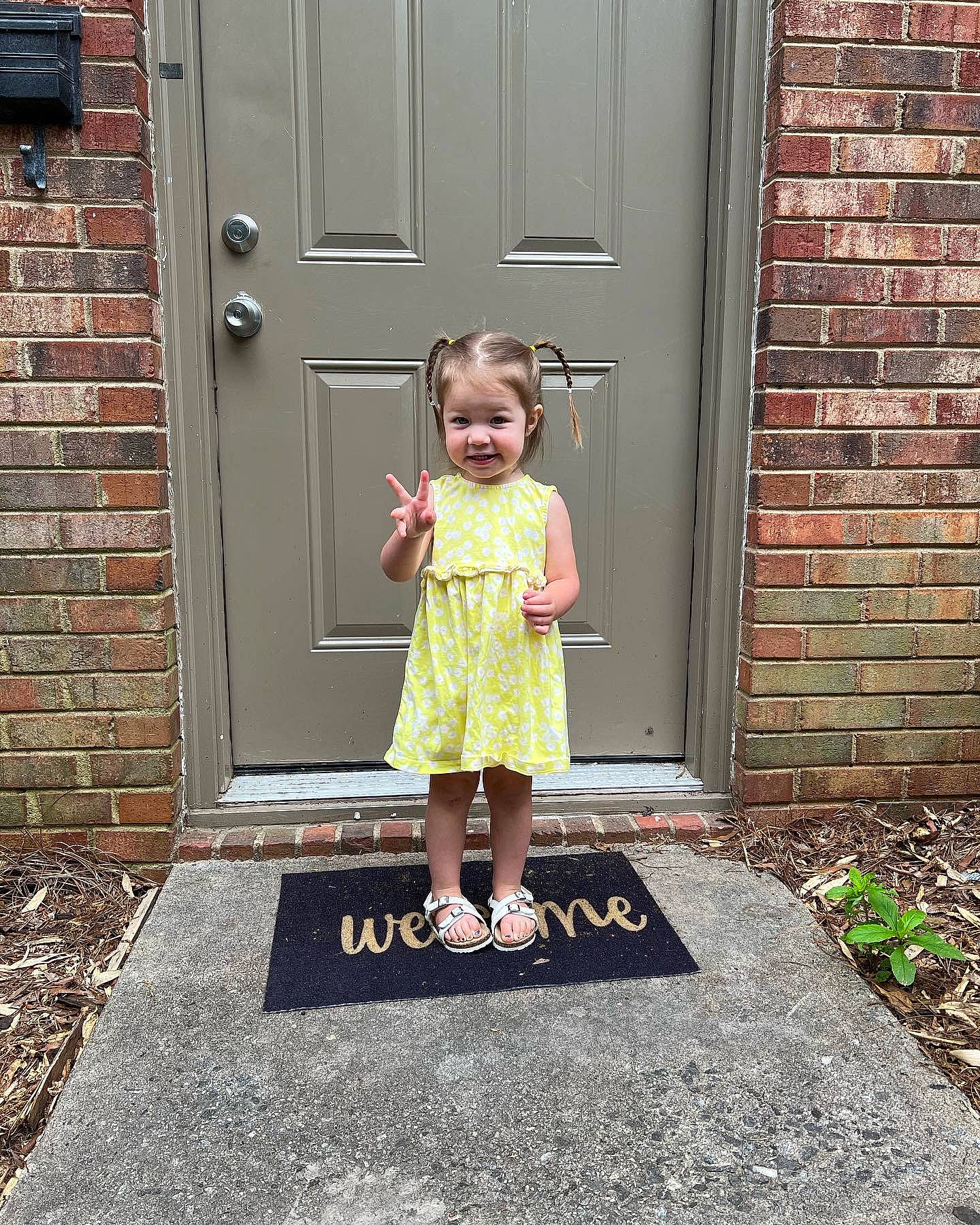 Weslyn is registered to the contest to win money with this photo: asphalt, baby_toddler_clothing, brick, brickwork, child, door, dress, flooring, grass, home_door, house, human_leg, magenta, person, road_surface, smile, standing, toddler, tree, window