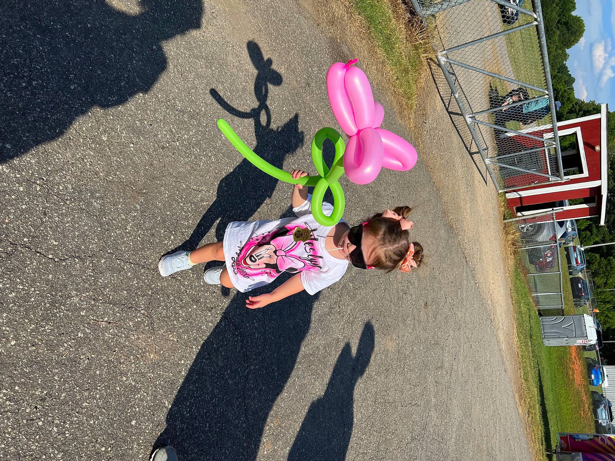 Weslyn is registered to the contest to win money with this photo: asphalt, city, fun, grass, leisure, magenta, pedestrian, plant, recreation, road, road_surface, shadow, sidewalk, soil, street, tar, toddler, toy, tree