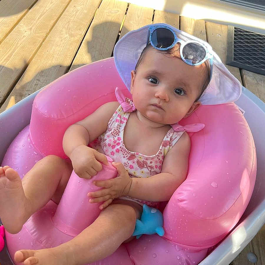 Liya a rejoint le concours — aidez-le/la à gagner de superbes lots ! baby, bath_toys, child, clothing, cute, foot, hand, inflatable_seat, outdoor, person, pink, playful, relaxing, serious_expression, summer, sunglasses, sunhat, tub, water, wooden_deck