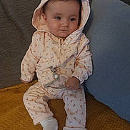 Liya participe au concours pour gagner de l'argent avec cette photo : baby, child, hoodie, pink_clothing, socks, couch, pillow, blanket, indoor, infant, cute, seated, face, expression, hand, legs, fabric, pattern, relaxed, home
