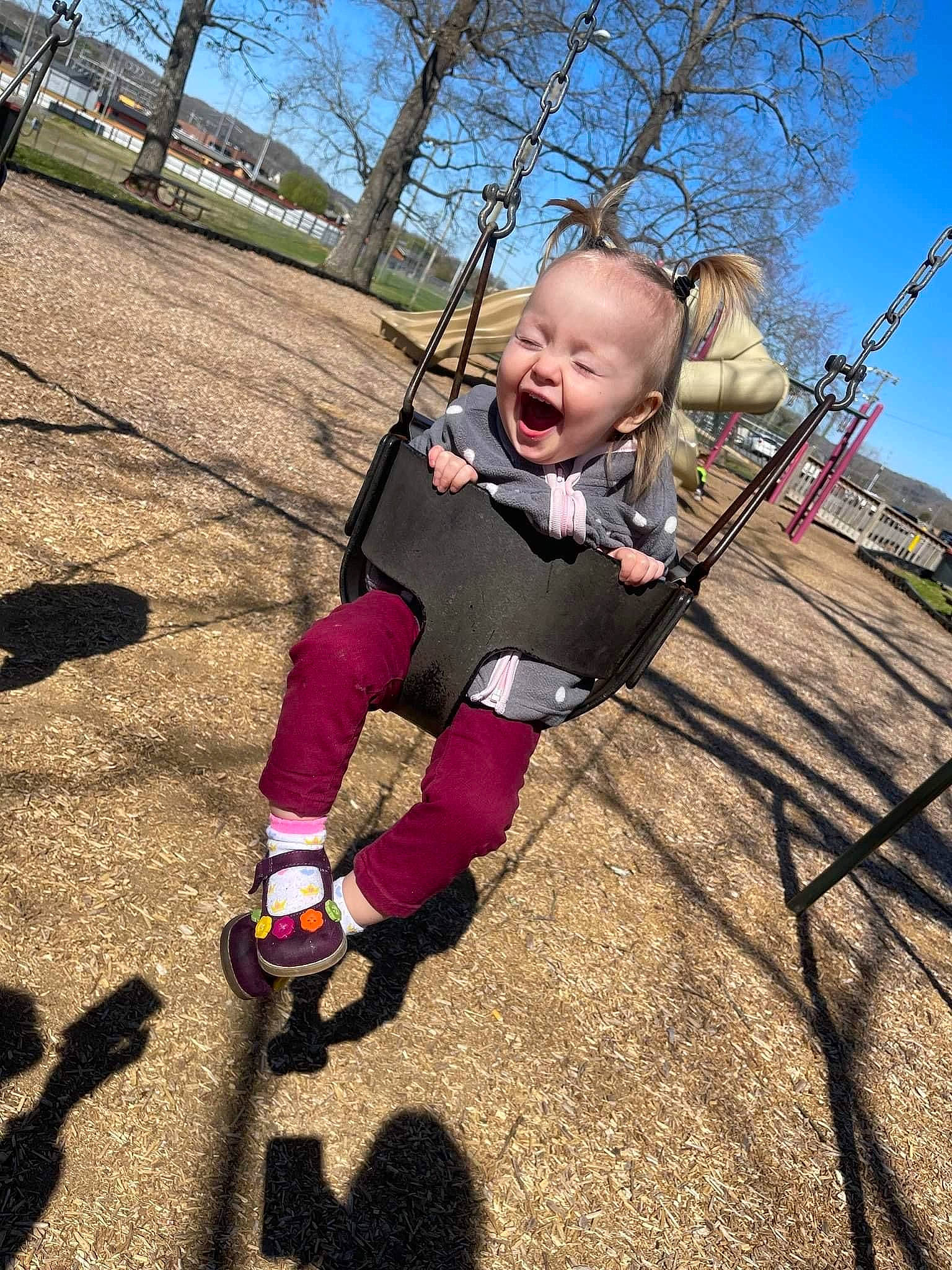 Harper is registered to the contest to win money with this photo: baby, baby_toddler_clothing, city, eye, face, fun, grass, happy, leisure, outdoor_play_equipment, person, playground, recreation, sky, smile, sock, soil, spring, swing, toddler