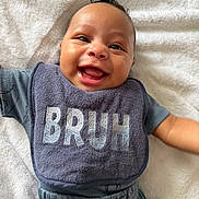 Cristian is registered to the contest to win money with this photo: baby, smiling, bib, towel, happy, infant, clothing, portrait, cute, child, face, expression, laying_down, head, skin, hair, apparel, young_child, one_person, indoor