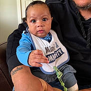 Cristian joined the competition — help win amazing prizes! baby, infant, adult, tattoo, bib, clothing, hand, face, person, indoor, furniture, couch, sitting, reaching, expression, skin, hoodie, closeup, parent, child