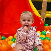 Luna participe au concours pour gagner de l'argent avec cette photo : child, toddler, ball_pit, slide, playground, indoor_playground, colorful, orange_balls, yellow_balls, green_ball, white_ball, sitting, portrait, cute, infant, clothing, hand, play, baby, fun