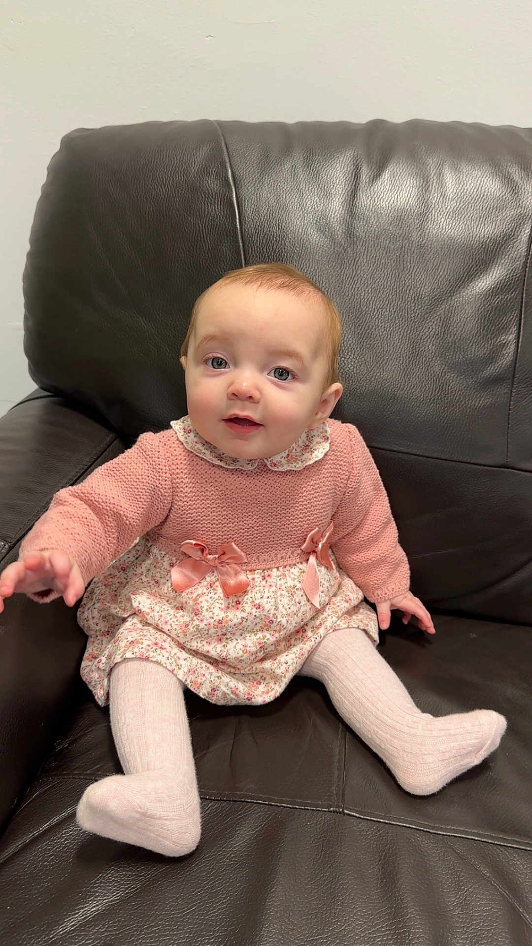 Kienna-Jo is registered to the contest to win money with this photo: baby, child, infant, pink_sweater, floral_dress, tights, leather_couch, sitting, indoor, cute, young_child, portrait, person, furniture, expression, hand, footwear, knitted, cozy, smiling