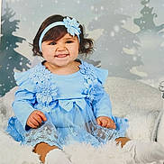 Lara Felgueiras a rejoint le concours — aidez-le/la à gagner de superbes lots ! baby, child, blue_dress, headband, flower, smile, tongue_out, sitting, blanket, white_socks, winter_theme, snowflakes, background, cute, portrait, indoor, studio_photo, happy, toddler, fuzzy_texture