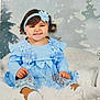baby, child, blue_dress, headband, flower, smile, tongue_out, sitting, blanket, white_socks, winter_theme, snowflakes, background, cute, portrait, indoor, studio_photo, happy, toddler, fuzzy_texture
