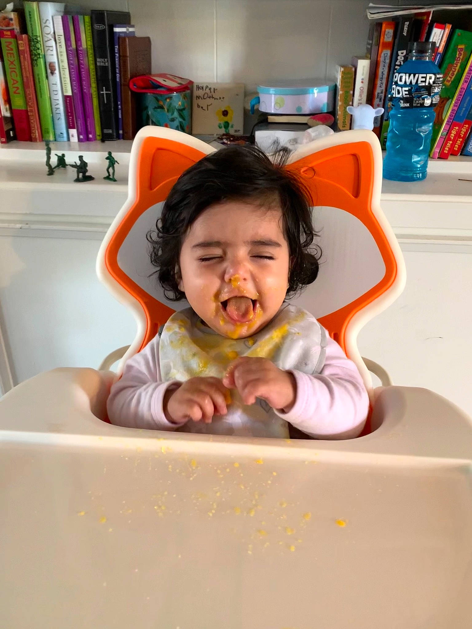 Meadow is registered to the contest to win money with this photo: baby, baby_toddler_clothing, book, bookcase, chair, child, comfort, fun, happy, human_body, laugh, leisure, person, play, room, shelf, shelving, sitting, smile, t_shirt