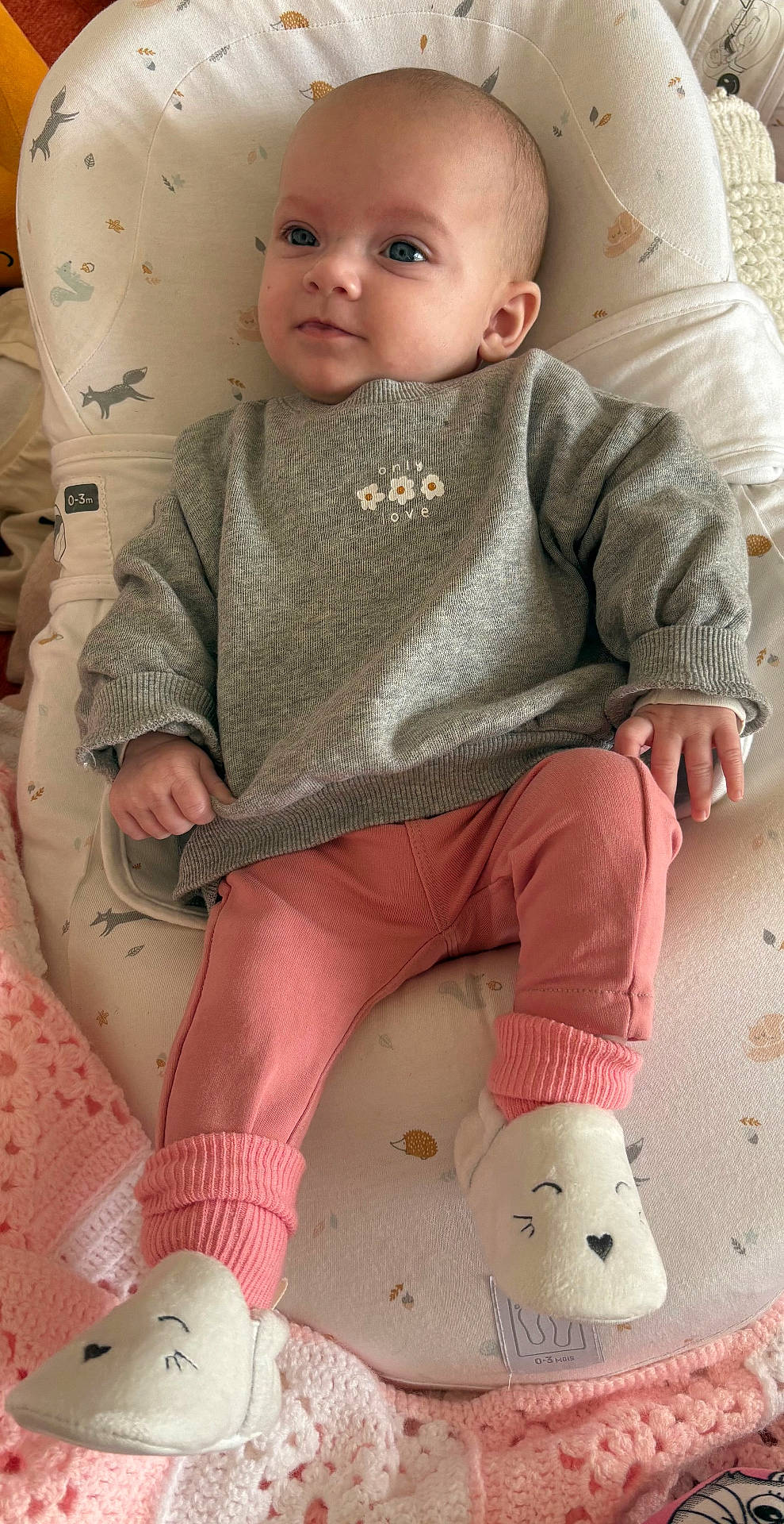 Adria a rejoint le concours — aidez-le/la à gagner de superbes lots ! baby, blanket, child, clothing, cozy, cushion, cute, face, gray, hand, indoors, infant, pants, person, pink, seated, slippers, smiling_face_slippers, soft, sweater