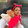 Skai joined the competition — help win amazing prizes! toddler, child, pink_outfit, headband, mini_chair, white_chair, curious, outdoor, reflection, car, black_car, knitted_clothing, baby, reaching_hand, portrait, cute, smiling, african_american, hair, daylight