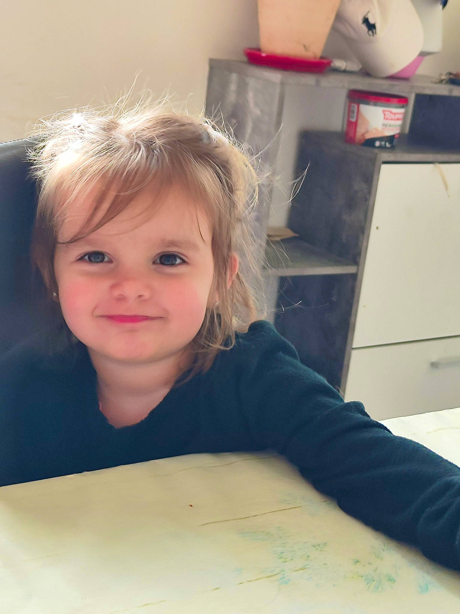 Kelsy a rejoint le concours — aidez-le/la à gagner de superbes lots ! blond, cabinetry, child, drawer, eyelash, face, floor, flooring, happy, home_appliance, joy, kitchen, person, room, sitting, smile, standing, t_shirt, table, toddler