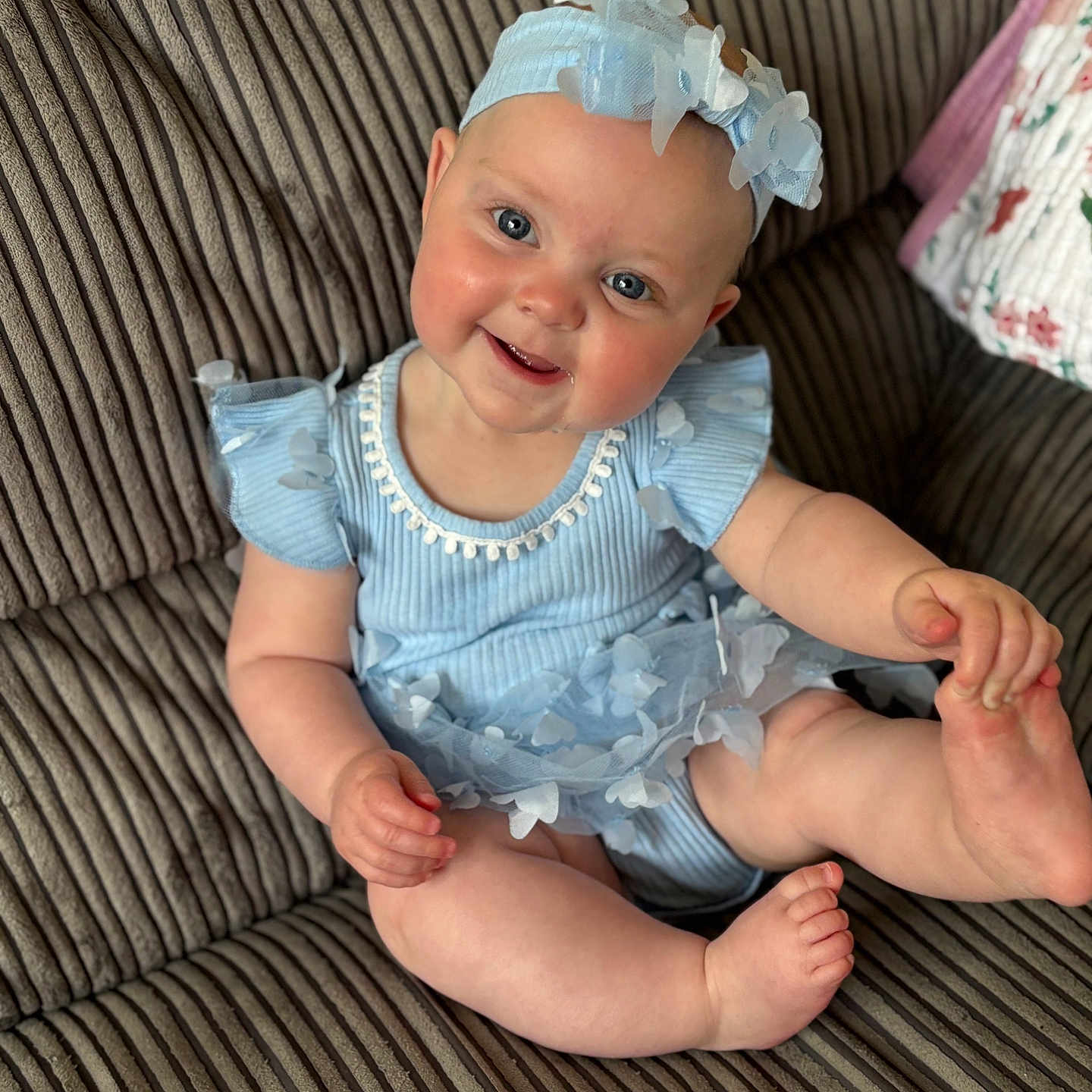 Aliya is registered to the contest to win money with this photo: baby, blue_dress, child, clothing, couch, cute, face, foot, furniture, hand, happy, headband, headwear, indoor, infant, person, portrait, sitting, skin, smiling