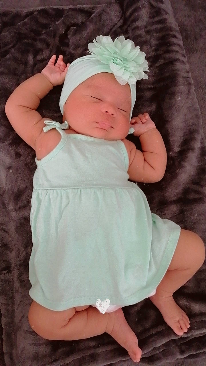 Eva a rejoint le concours — aidez-le/la à gagner de superbes lots ! baby, baby_toddler_clothing, child, comfort, face, finger, flower, gesture, grass, head, headgear, leg, pattern, person, pink, plant, skin, sleeve, thumb, toddler