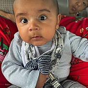 Isaiah is registered to the contest to win money with this photo: baby, child, infant, person, clothing, striped_shirt, bib, car_seat, seat, fabric, red_clothing, playful, face, eyes, expression, background, indoor, vehicle, casual, cute