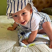 Hunner is registered to the contest to win money with this photo: baby, child, crawling, hat, striped_clothing, bed, blanket, smiling, happy, indoor, person, cute, playful, infant, skin, headwear, white, blue, fabric, closeup