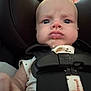 baby, infant, car_seat, harness, drool, face, expression, serious, child, young, clothing, seatbelt, safety, cute, closeup, skin, person, head, indoors, black