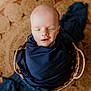 newborn, baby, sleeping, wrapped, blanket, basket, woven, blue, peaceful, infant, head, closed_eyes, portrait, cozy, soft, warm, indoors, floor, round_rug, cute