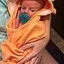 baby, infant, pacifier, towel, orange, hooded_towel, wrapped, cradled, arms, hand, skin, indoor, person, newborn, comfort, soft, cute, child, portrait, care
