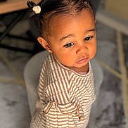 Izïa a rejoint le concours — aidez-le/la à gagner de superbes lots ! toddler, child, striped_clothing, hair_buns, earrings, portrait, indoor, soft_lighting, cute, young_child, person, curly_hair, expression, seated, carpet, table, floor, furniture, skin, closeup