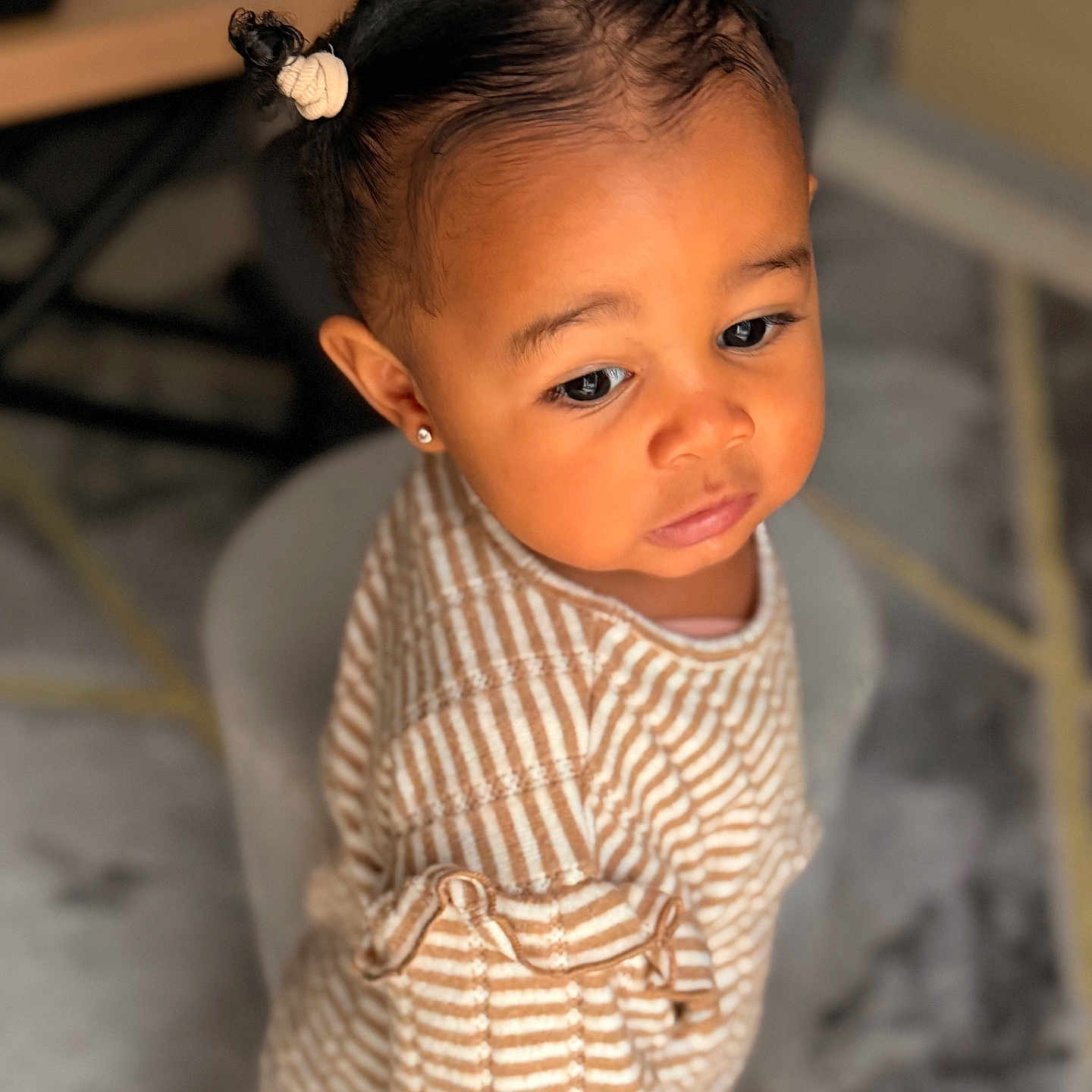 Izïa a rejoint le concours — aidez-le/la à gagner de superbes lots ! carpet, child, closeup, curly_hair, cute, earrings, expression, floor, furniture, hair_buns, indoor, person, portrait, seated, skin, soft_lighting, striped_clothing, table, toddler, young_child