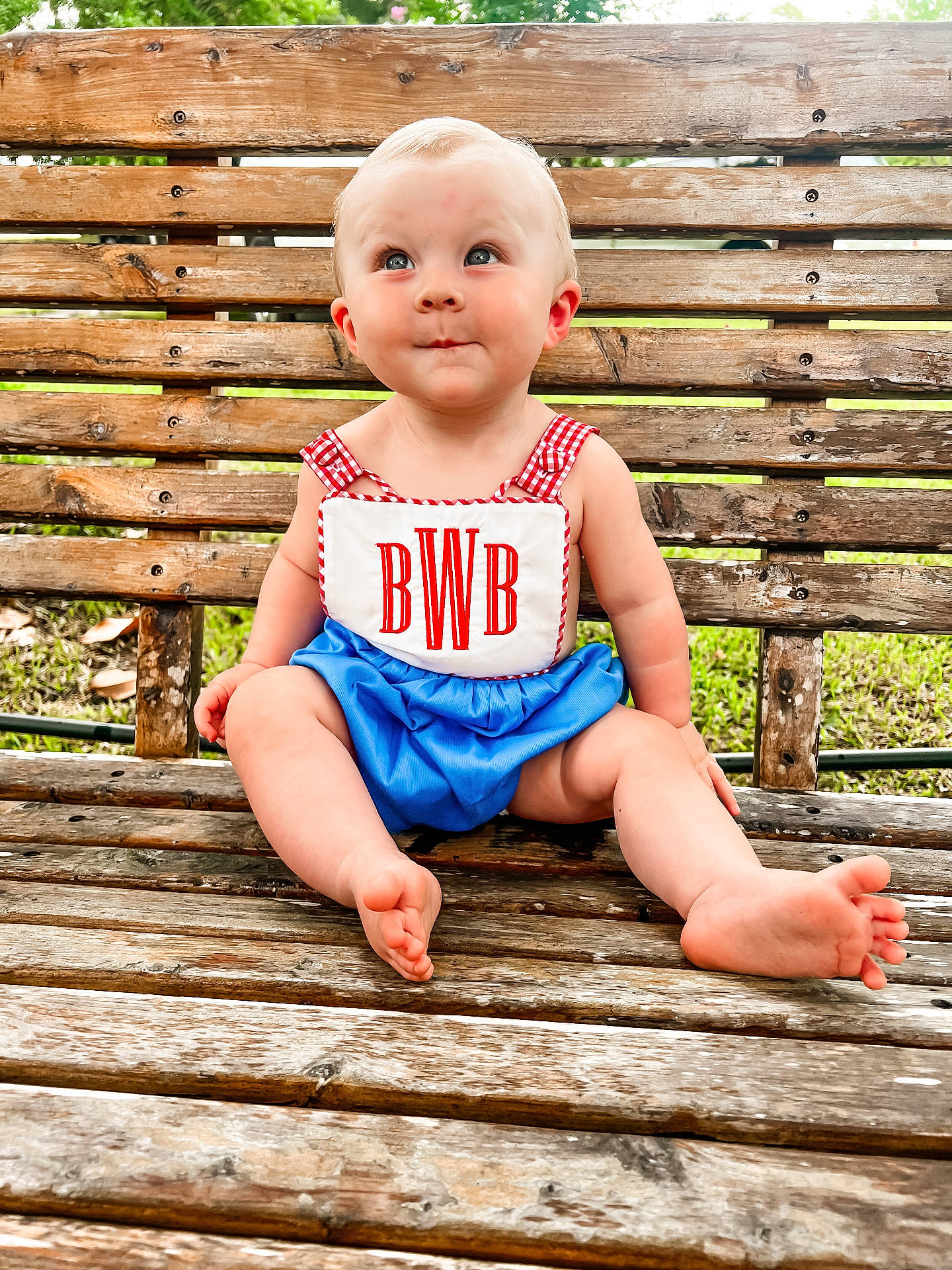 Bowen is registered to the contest to win money with this photo: baby, bench, bodypart, clothing, dress, face, finger, furniture, grass, hand, hardwood, head, person, photography, plant, portrait, shorts, sitting, t_shirt, wood