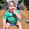 baby, child, headband, bow, green_shirt, rainbow, smile, fingers_in_mouth, shorts, sand, outdoor, sunny, plants, strawberries, field, nature, portrait, happy, sitting, person