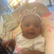 Zoey joined the competition — help win amazing prizes! baby, infant, headband, bow, blanket, cushion, seat, indoor, soft_light, child, cute, smiling, clothing, hand, face, person, pattern, window, daylight, relaxed