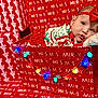 Iris joined the competition — help win amazing prizes! baby, infant, christmas, holiday, festive, red, box, wrapping_paper, lights, headband, clothing, cute, portrait, indoors, cozy, pillow, decoration, celebration, child, smiling
