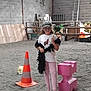 Clara a rejoint le concours — aidez-le/la à gagner de superbes lots ! child, girl, glasses, hat, feather, black_feather_boa, traffic_cone, pink_block, indoor, sandy_floor, brick_wall, ladder, wooden_fence, casual_clothing, white_tshirt, leggings, flip_flops, playful, toy, accessory