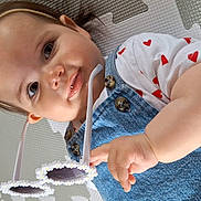 Ava joined the competition — help win amazing prizes! baby, child, girl, bow, polka_dot, headband, sunglasses, denim_overalls, white_shirt, heart_pattern, play_mat, hand, face, eyes, smile, skin, infant, cute, indoor, closeup