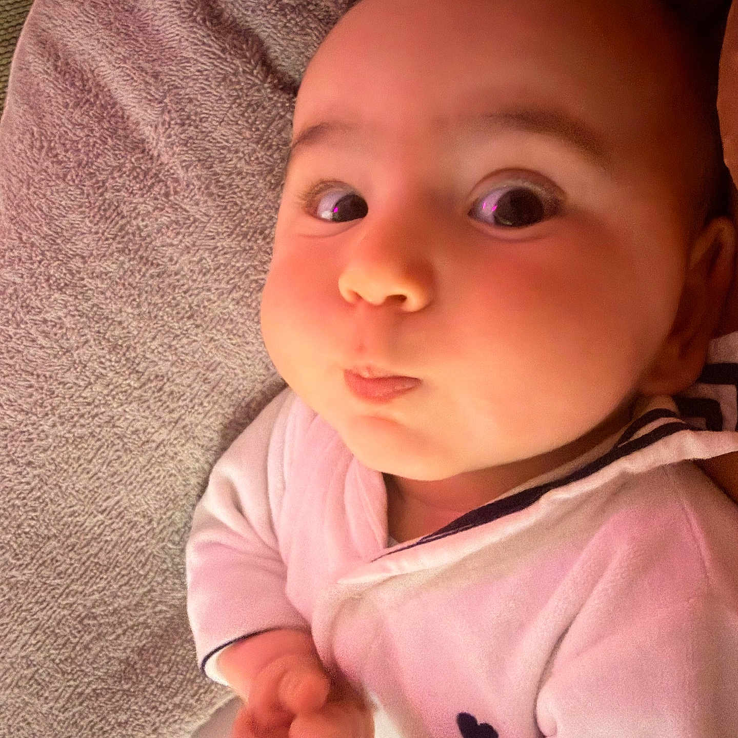 Isaac a rejoint le concours — aidez-le/la à gagner de superbes lots ! baby, infant, face, wide_eyes, pursed_lips, white_outfit, heart_detail, blanket, texture, hand, cute, portrait, child, indoors, soft_lighting, skin, expression, sleepwear, closeup, person