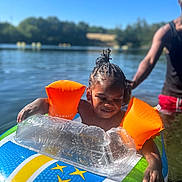 Keylane participe au concours pour gagner de l'argent avec cette photo : child, lake, water, inflatable, float, arm_floaties, summer, sunny, outdoor, person, braids, swimming, recreation, nature, adult, playful, water_safety, blue_sky, greenery, fun