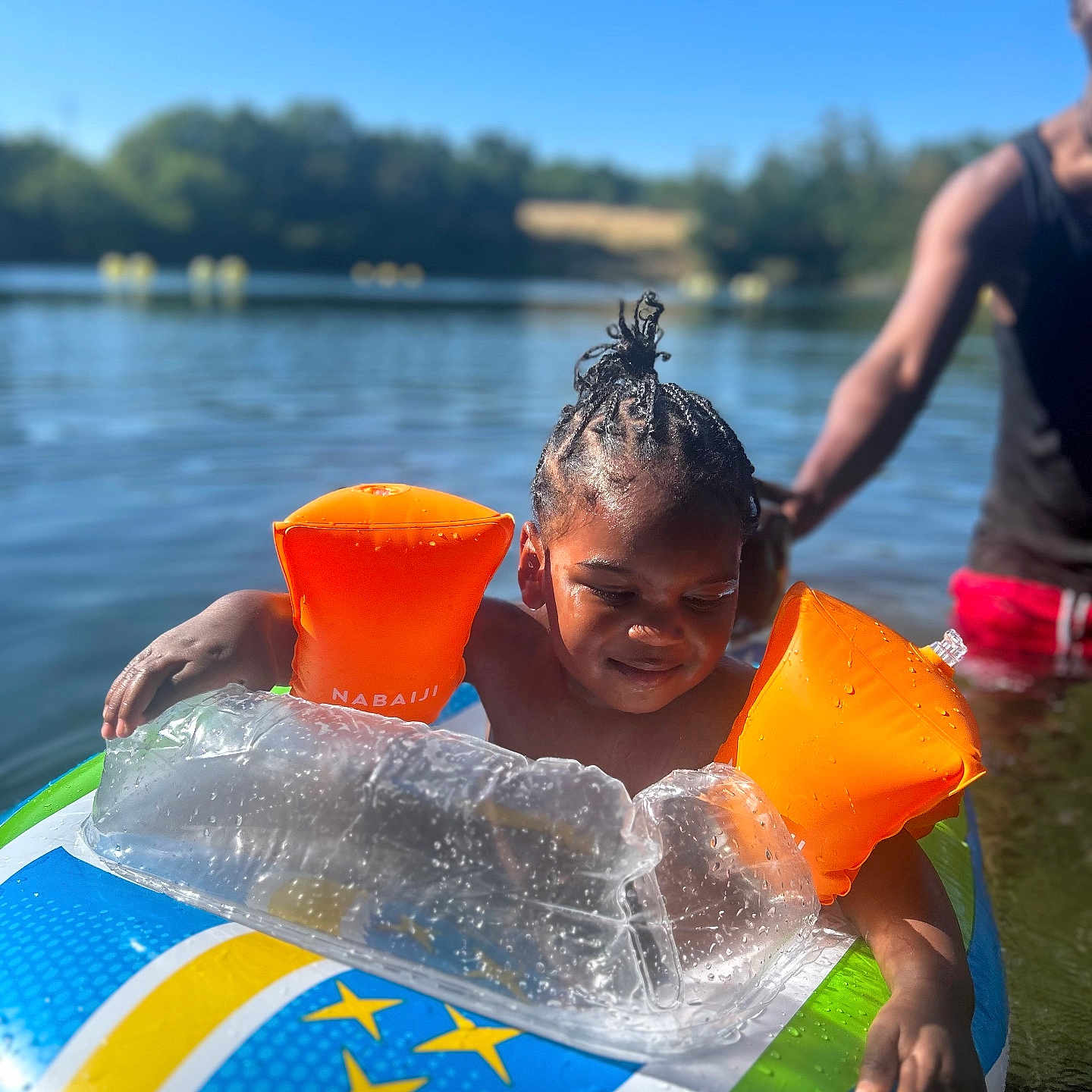 Keylane participe au concours pour gagner de l'argent avec cette photo : adult, arm_floaties, blue_sky, braids, child, float, fun, greenery, inflatable, lake, nature, outdoor, person, playful, recreation, summer, sunny, swimming, water, water_safety