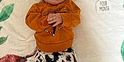 Alaya is registered to the contest to win money with this photo: baby, infant, child, lying_down, blanket, headband, cow_print, orange_sweater, pants, tongue_out, cute, smiling, four_month, decor, leaf_pattern, animal_print, cozy, indoor, portrait, playful
