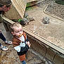 child, toddler, pacifier, adult, tortoise, glass_enclosure, wooden_structure, zoo, footwear, floor, animal, reptile, observation, curious, brown_clothing, casual_wear, indoor, person, nature, daylight