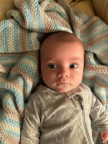 Bensyn is registered to the contest to win money with this photo: baby, baby_toddler_clothing, brown, cheek, child, chin, close_up, comfort, eye, eyebrow, eyelash, iris, linens, mouth, nose, outerwear, person, sitting, skin, sleeve