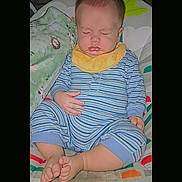 Koah joined the competition — help win amazing prizes! baby, infant, sleeping, sitting, striped_clothing, pajamas, yellow_bib, barefoot, crossed_feet, blanket, quilt, bed, nursery, portrait, indoor, cozy, face, closed_eyes, child, colorful_background