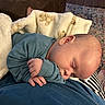 William is registered to the contest to win money with this photo: baby, sleeping, blanket, teddy_bear_pattern, blue_clothing, hand, face, head, indoor, lap, comfort, wood_floor, rug, striped_clothing, person, cozy, peaceful, rest, infant, closeup