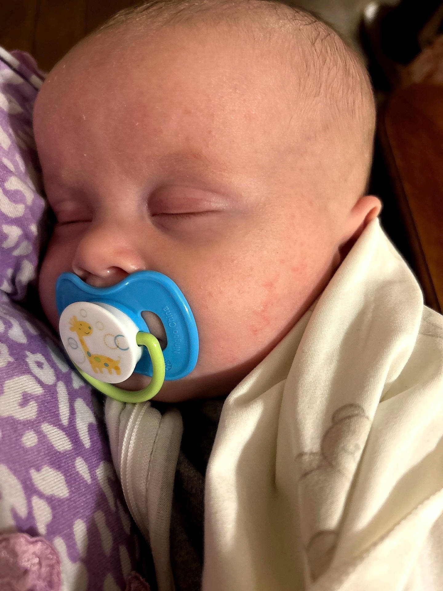 William is registered to the contest to win money with this photo: baby, blanket, blue, child, closeup, cozy, cute, face, giraffe, indoors, infant, newborn, pacifier, peaceful, portrait, purple, resting, sleeping, soft, white_cloth