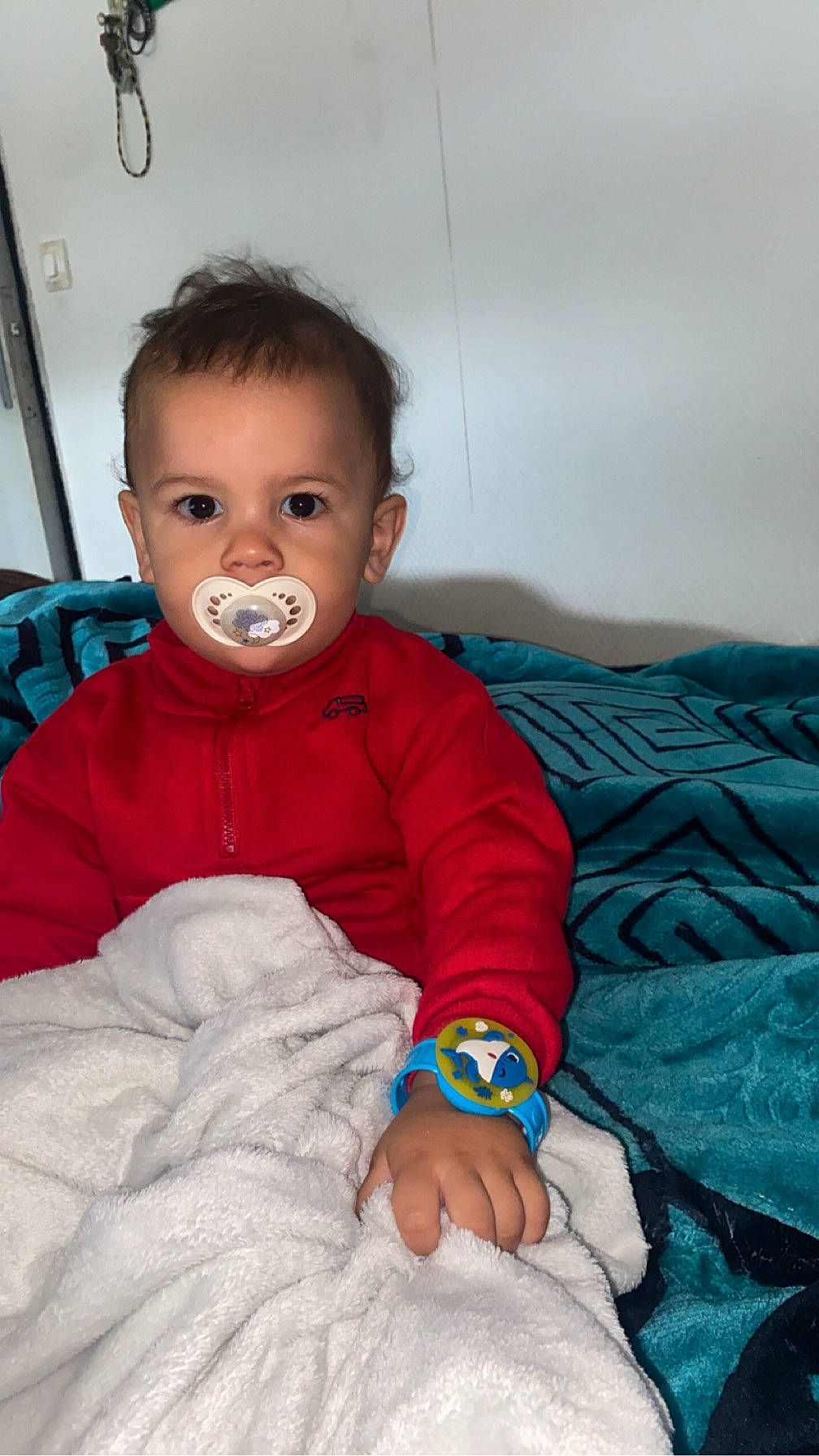 Yslem participe au concours pour gagner de l'argent avec cette photo : baby, baby_toddler_clothing, bedding, cheek, child, comfort, eye, finger, fun, happy, iris, linens, magenta, mouth, nose, person, room, sitting, skin, sleeve