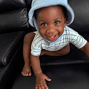 Dale is registered to the contest to win money with this photo: toddler, child, baby, hat, blue, striped_shirt, crawling, smiling, happy, black_leather_couch, furniture, indoor, person, cute, playful, motion_blur, young_child, skin, hand, foot
